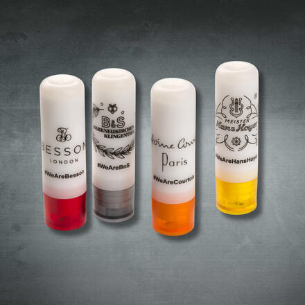 Vier Lippenpflegestifte aus Kunststoff in weiß mit Firmenlogos in schwarz bedruckt, farbige Deckel in rot, grau, orange, gelb auf neutralem Hintergrund fotografiert Vier Lippenpflegestifte aus Kunststoff in weiß mit Firmenlogos in schwarz bedruckt, farbige Deckel in rot, grau, orange, gelb auf neutralem Hintergrund fotografiert