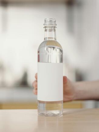 Weißer Essig in Plastikflasche wird auf einen Tisch gestellt ohne Label.