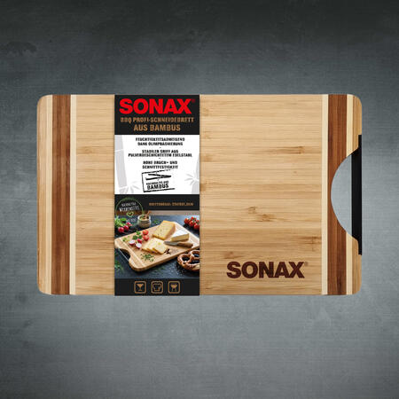 Bambus-Schneidebrett mit schwarzem Griff und aufgebrachter Produktbanderole liegt auf grauem Hintergrund