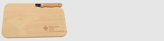 Holzschneidebrett aus Erlenholz mit eingestecktem Speckmesser und Logo-Lasergravur Schalk Kanalreinigung auf neutralem Hintergrund fotografiert