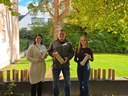 Drei Personen bei der Spendenübergabe im Augustinum mit Edelstahl-Trinkflaschen als Werbeartikel in Geschenkverpackung.