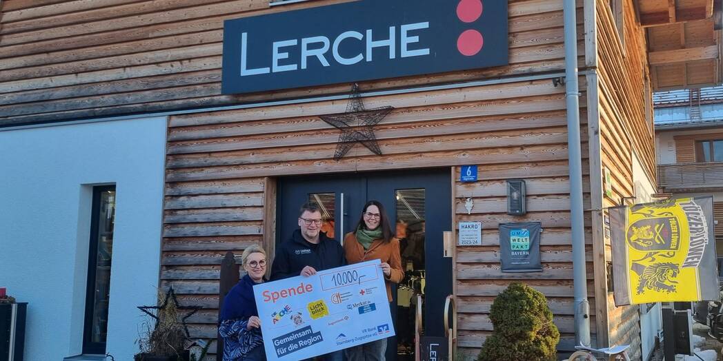 Drei Personenstehen nebeneinander und halten einen Spendencheck zusammen. Sie stehen vor der Eingangstür der Firma Lerche.