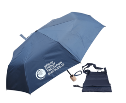 Dunkelblauer Taschenschirm mit hellem Holzgriff und passender Hülle danebenliegend. Auf einem Schirmsegment befindet sich ein weißer Aufdruck mit Text und Logo.
