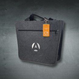 Graue Filztasche mit kurzem Tragegriff und Reißverschlussfach auf der Vorderseite. Eine orangefarbene Anhängekarte mit einem Lebensmittelsymbol hängt am Griff. Auf der Taschenfront ist ein schlichtes, weißes Logo aufgedruckt.