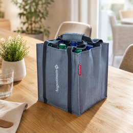 reisenthel Bottlebag in twist blue mit weißem Augustinum-Logo, befüllt mit Glasflaschen auf hellem Holztisch in warmer Wohnatmosphäre