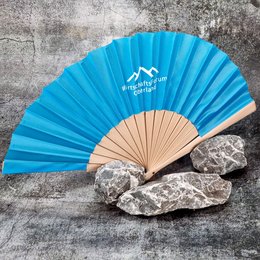 Blauer Werbefächer aus Textil mit hellem Holzgestell und weißem Logodruck „Wirtschaftsforum Oberland“ auf steinigem Hintergrund.