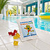Eine Fruchtgummitüte mit Frosch-Maskottchen des Thermelino Kinder-Clubs und ein paar Gummibärchen werden in einem Schwimmbad am Beckenrand dargestellt.