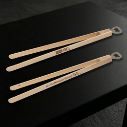 Zwei Grillzangen-Varianten mit Lasergravur auf schwarem Tisch als Jubiläumsgeschenk.