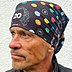 Mann trägt schwarzes Multifunktionstuch mit buntem Punktedesign und Jubiläumslogo 20 Jahre Lerche als Kopfbedeckung