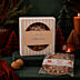 Lebkuchen als Werbemittel in beige-gestreifter Kartonverpackung mit Firmenlogo „andré-media“ abedruckt miot weihnachtlicher Dekoration fotografiert