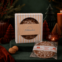Lebkuchen als Werbemittel in beige-gestreifter Kartonverpackung mit Firmenlogo „andré-media“ abedruckt miot weihnachtlicher Dekoration fotografiert