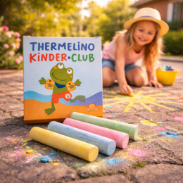 Straßenmalkreide mit bedruckter Verpackung „Thermelino Kinder-Club“ im Vordergrund während ein Kind draußen mit bunter Kreide malt.