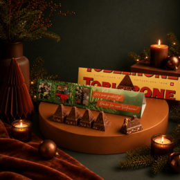 Individuell bedruckte Toblerone Verpackung mit Weihnachtsgrüßen und Schokoladenstücken in weihnachtlicher Dekoration