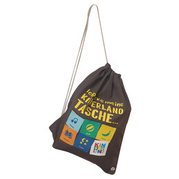Ein dunkelgrauer Turnbeutelmit heller Kordel, schräg aufgehängt fotografiert. Auf der Vorderseite steht in gelber Schrift „Ich packe meine Kinderland Tasche...“. Darunter sind fünf bunte Quadrate mit Symbolen und Texten: eine Note mit „Melodie“, ein Ball mit „Spaß“, eine Banane mit „Snack“, ein Buch mit „Märchen“, Sterne und Mond mit „Traum“ sowie ein buntes Logo mit der Aufschrift „Kinderland“.