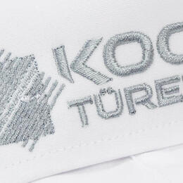 weißes Hemd liegt gefalten auf weißem Hintergrund. Auf dem Kragen ist ein Logo gestickt.