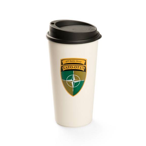 Ein naturfarbener Mehrwegbecher aus Kunststoff mit schwarzem Deckel. Auf der Vorderseite ist ein farbiges Wappen mit der Aufschrift „NATO-OTAN“ und einem Sternsymbol zu sehen. Der Becher steht vor weißem Hintergrund.