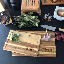 Akazienholz-Werbeschneidebrett mit umlaufender Saftrille und Lasergravur „Wuiderer Lounge“ in Küchenumgebung.