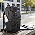 Schwarzer Deuter Daypack mit 25 L mit weißem Logoaufdruck, Trinkflaschenfach und Laptopfach im Business-Umfeld auf Holzbank.